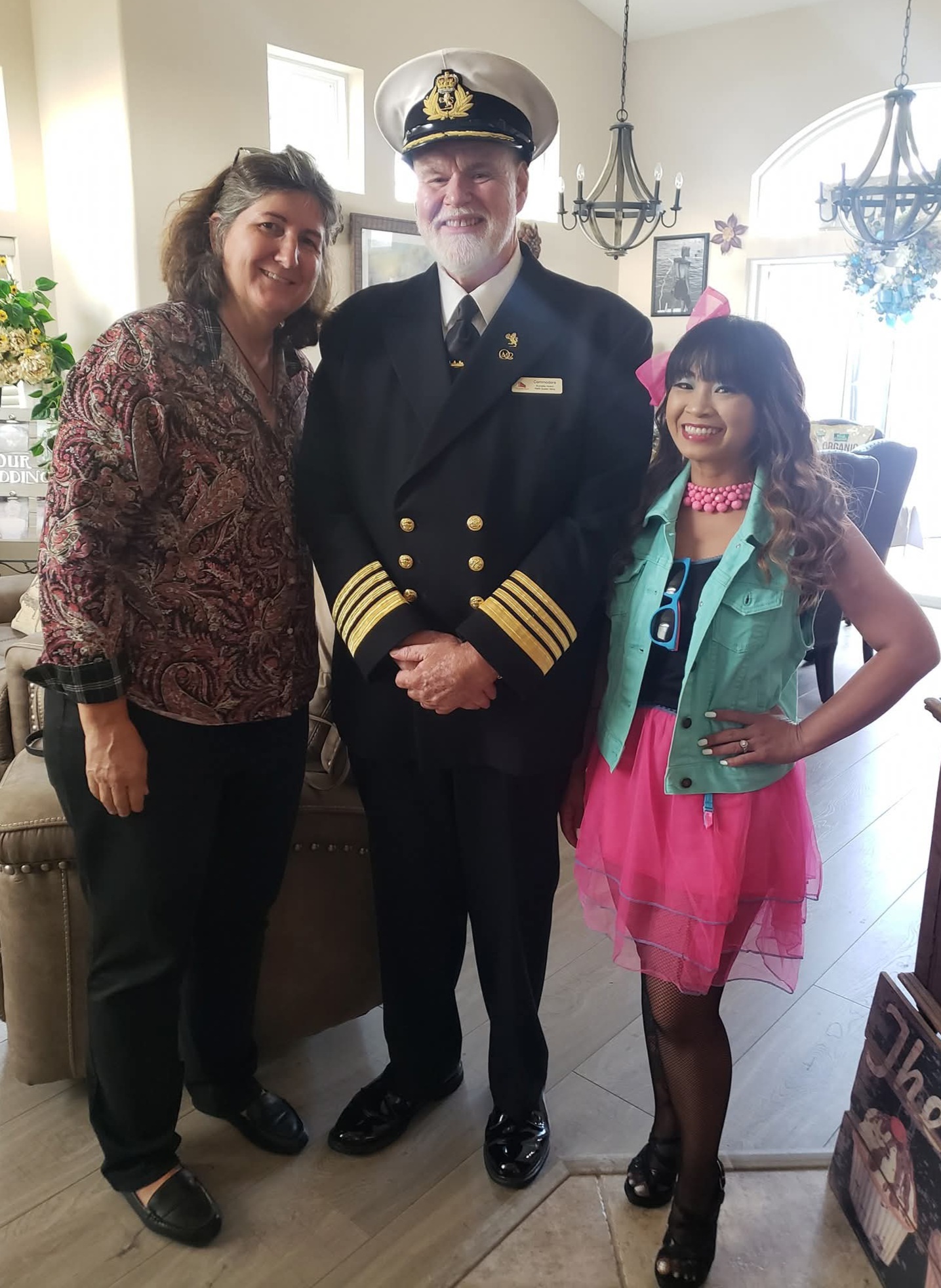 a man in uniform with two women in a room